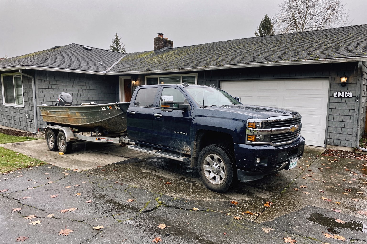 Abandoned 16-foot fishing boat loaded on trailer attached to pickup truck ready for removal in Washington residential driveway