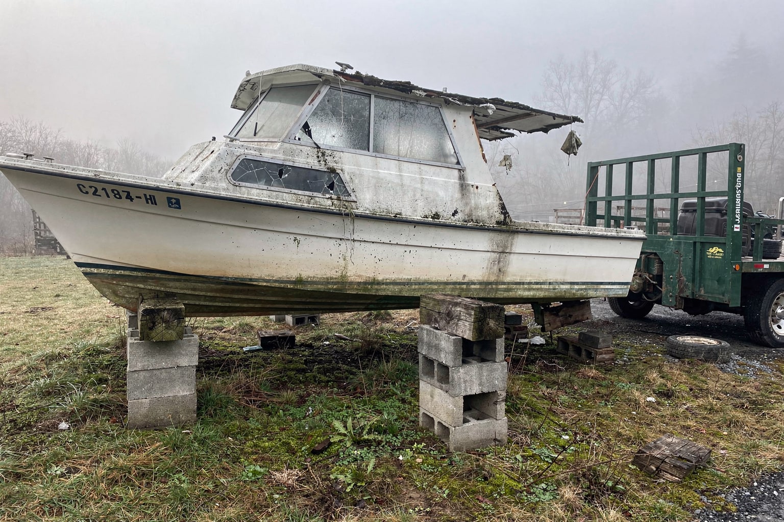 Junk boat on wooden stands with flatbed truck ready for West Virginia marine salvage pickup