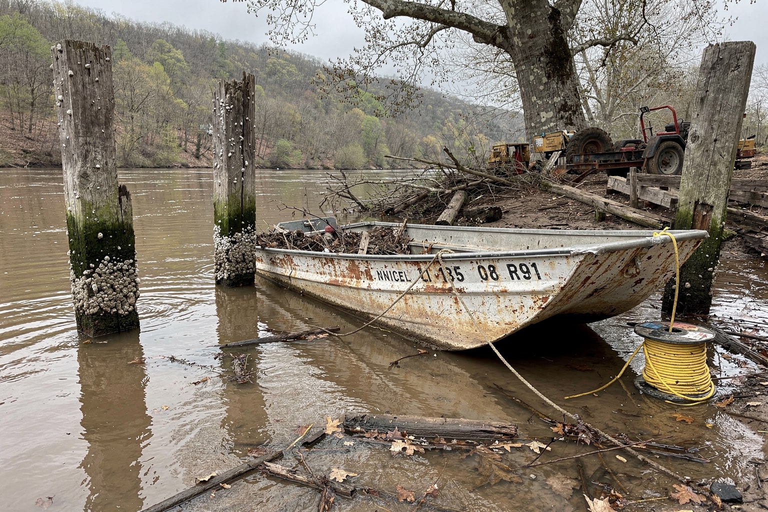 Sinking junk boat at West Virginia river dock with salvage equipment staged for removal