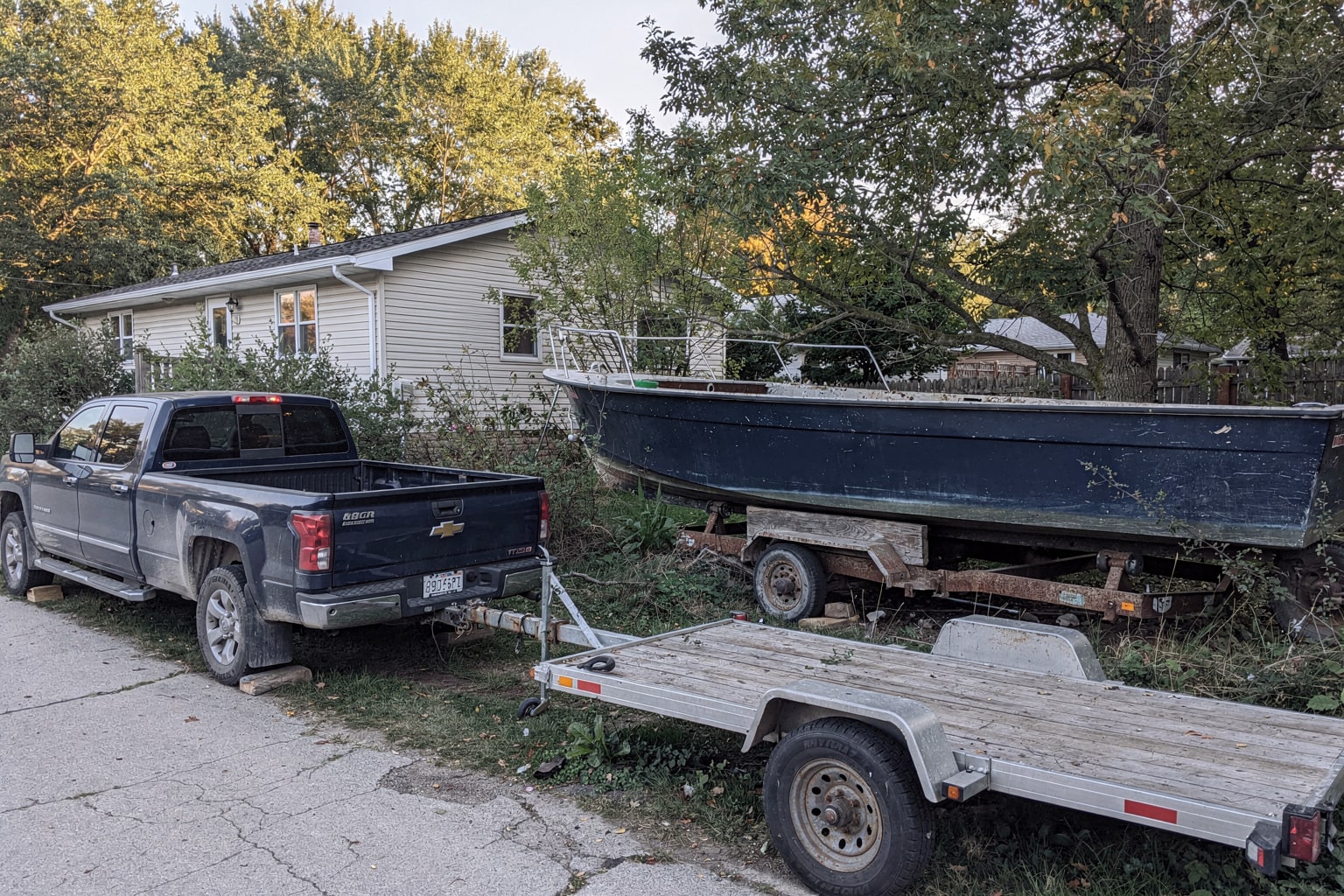 Large fiberglass cabin cruiser junk boat removal from overgrown Wisconsin yard with pickup truck
