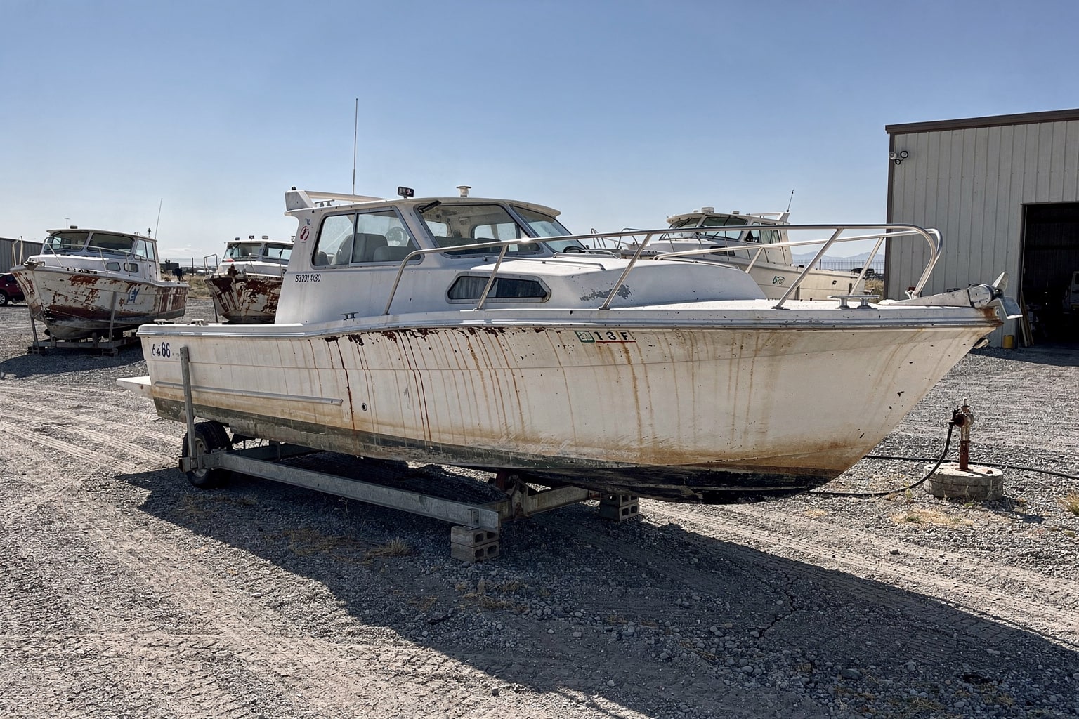 Weathered 22-foot cabin cruiser on steel cradle at Wyoming boatyard marine salvage facility