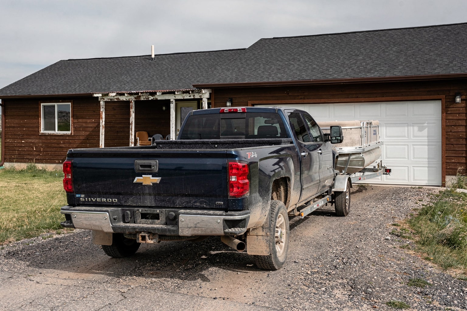 Weathered 20-foot pontoon boat loaded on trailer behind pickup truck, Wyoming residential boat removal