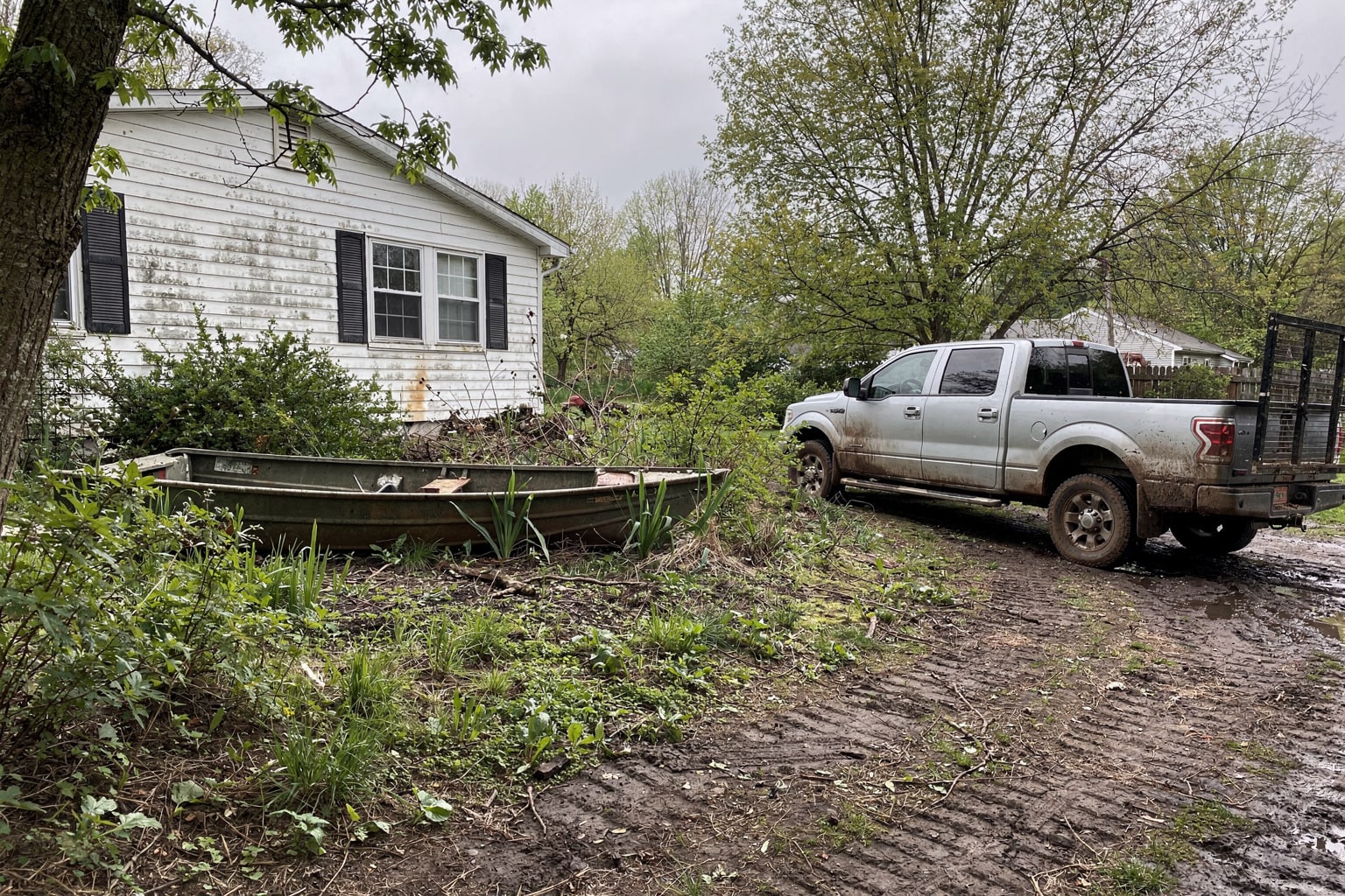 Abandoned 18-foot aluminum jon boat salvage removal in overgrown Delaware property with pickup truck