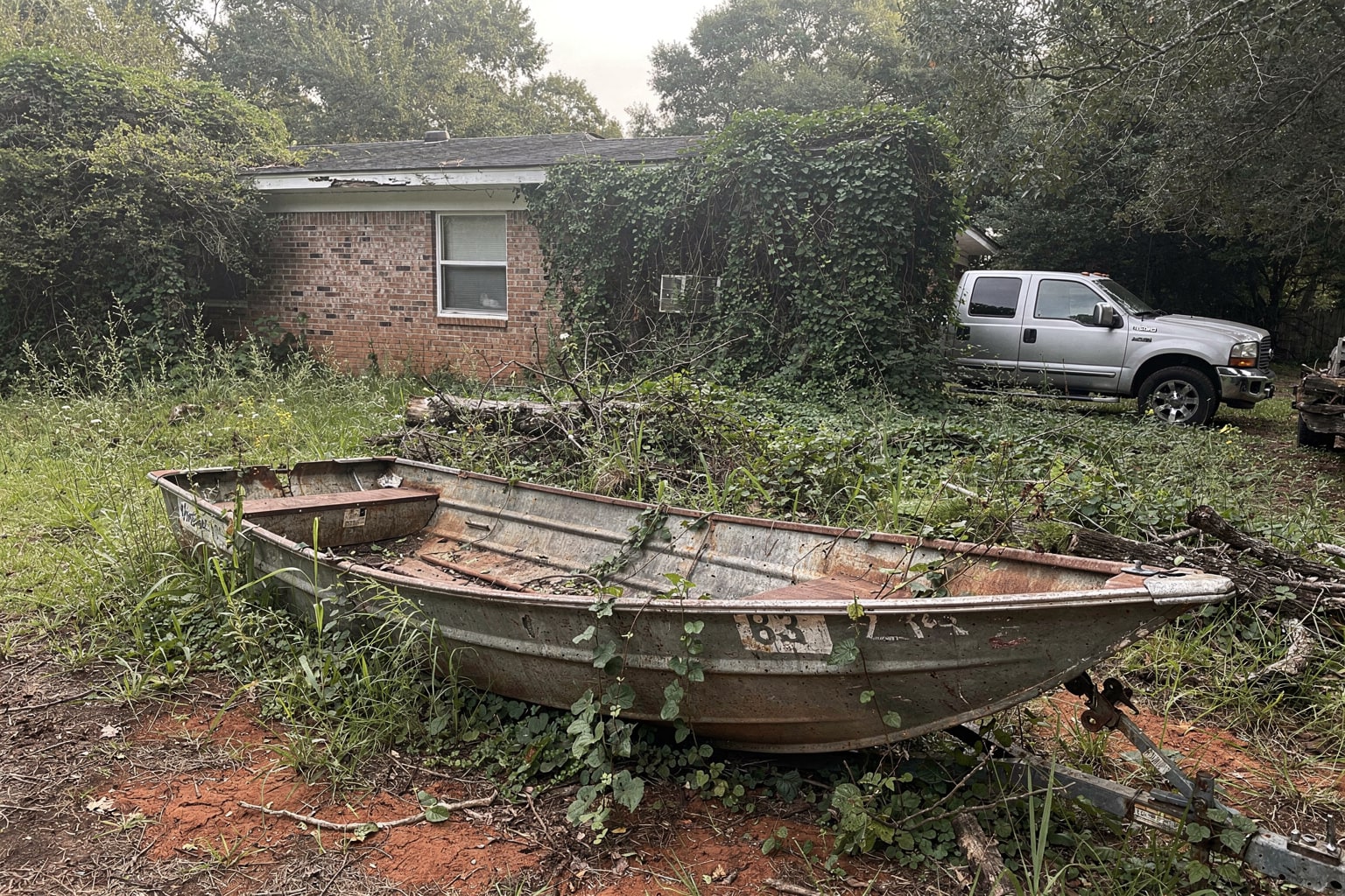 Junk boat disposal South Carolina, abandoned deteriorated aluminum boat removed from overgrown property