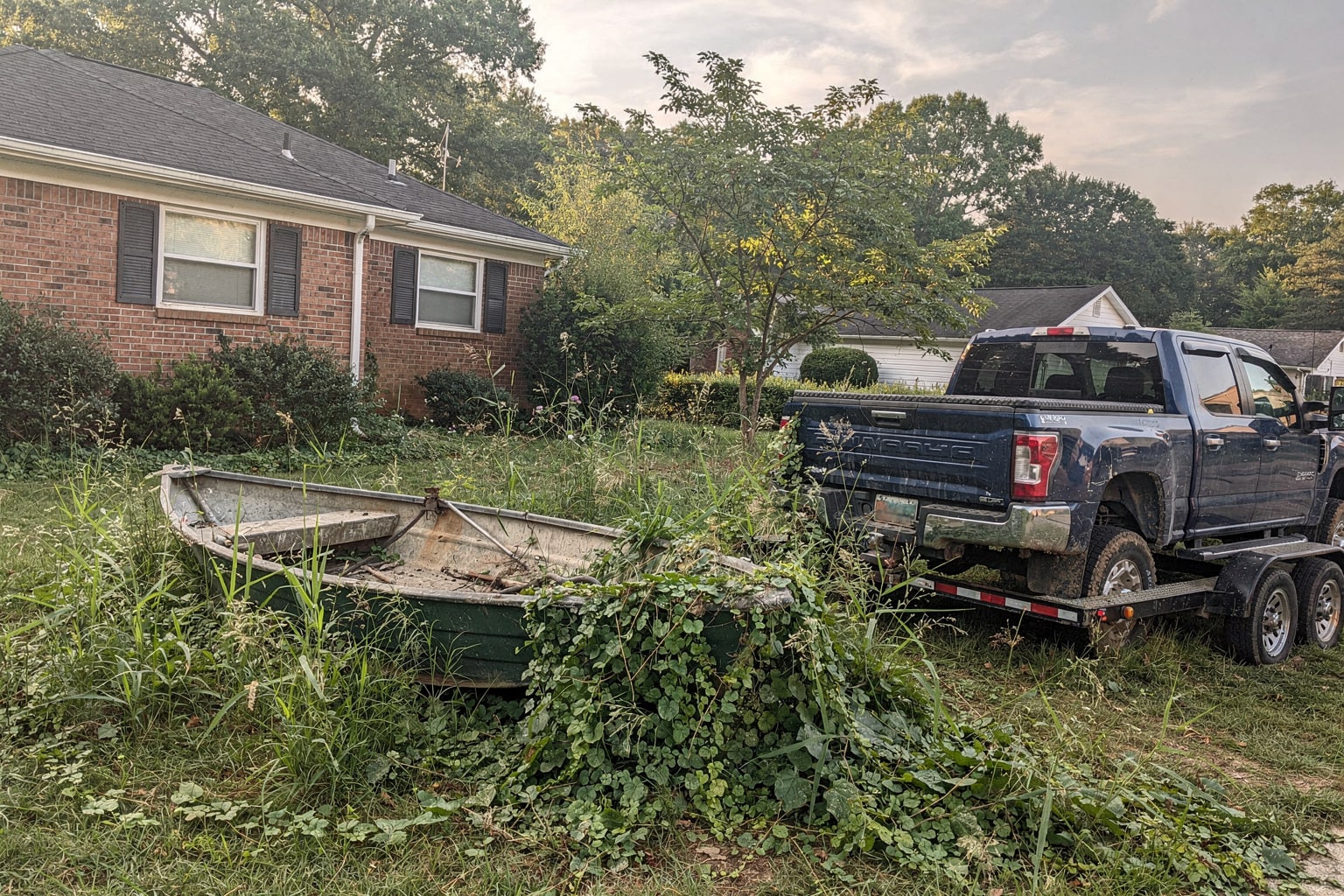Junk boat removal Atlanta overgrown yard with pickup truck trailer hauling