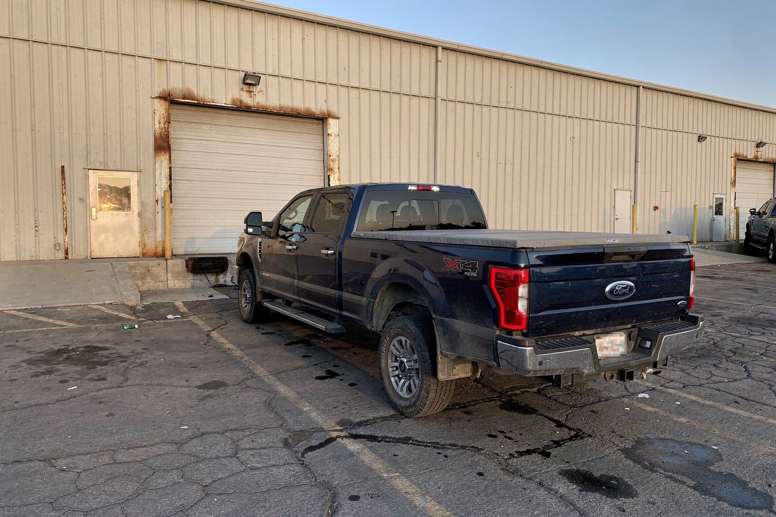 Junk boat removal Bakersfield commercial lot weathered cruiser on tandem trailer