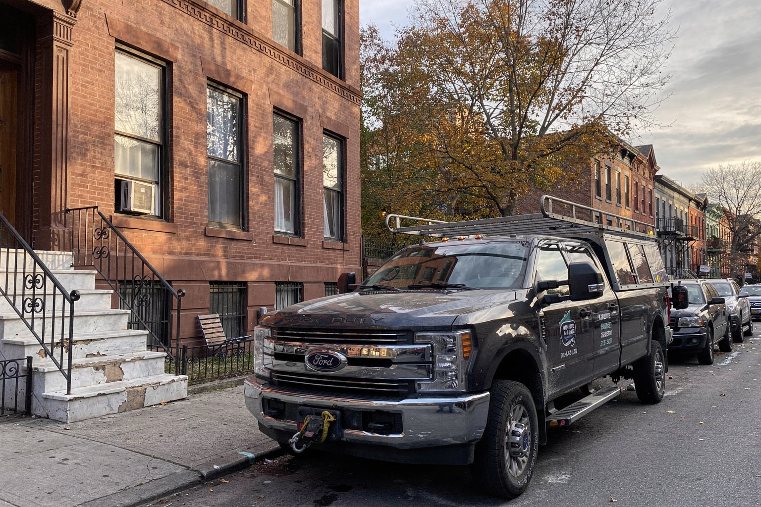 Professional junk boat removal Brooklyn—large cabin cruiser on tandem trailer with Hansons branded truck