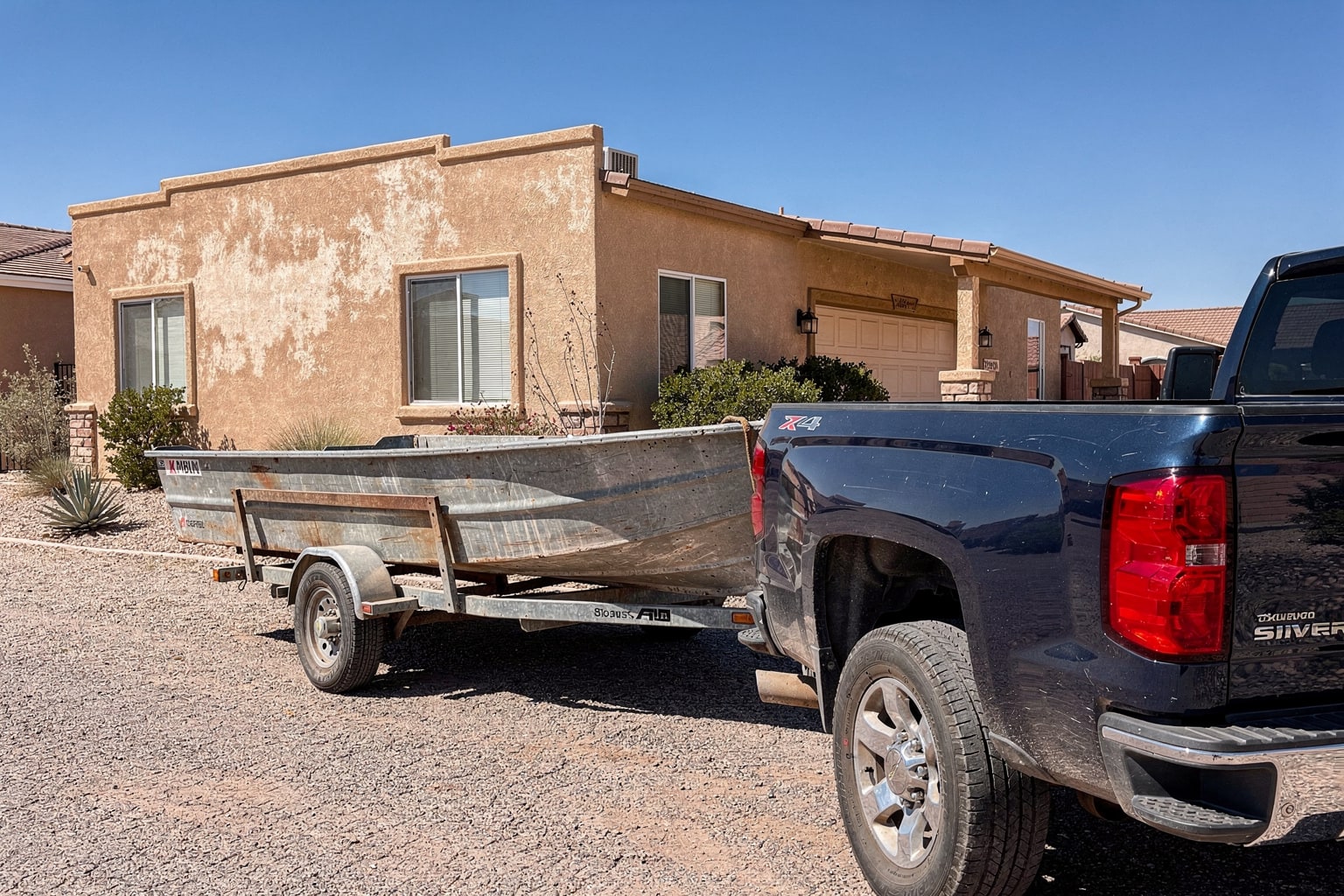 Weathered aluminum junk boat on trailer, El Paso boat removal service, Texas residential driveway