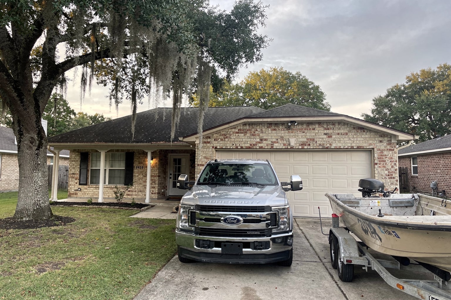 Empty boat removal trailer behind pickup truck in Houston residential driveway ready for junk boat disposal service
