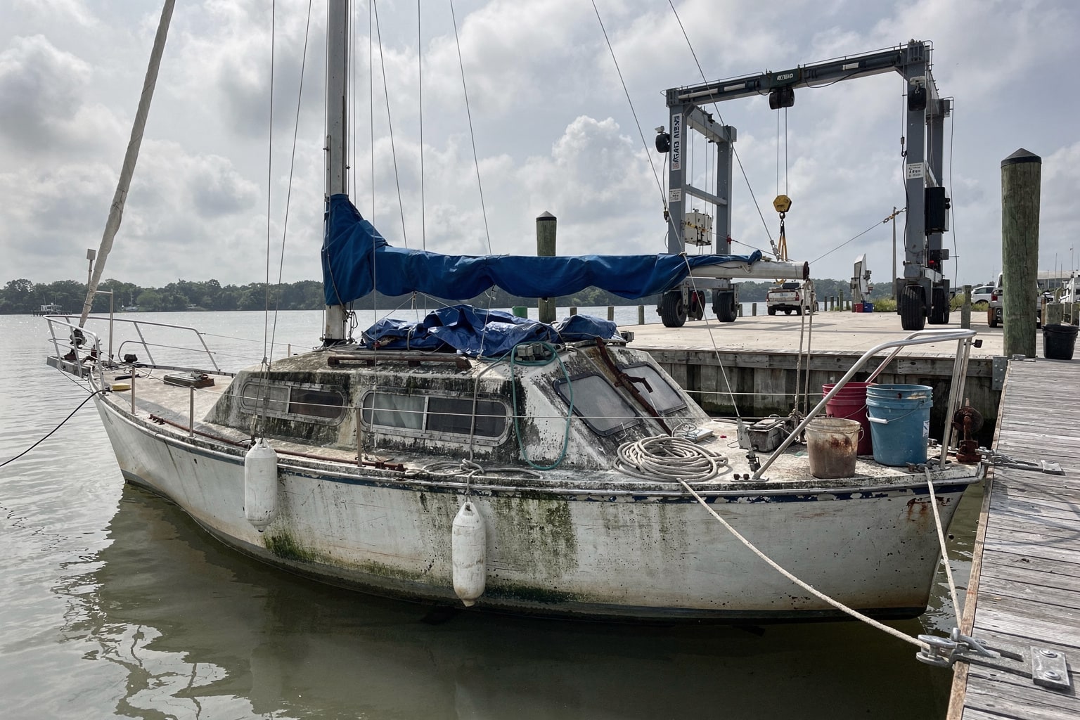 Junk boat removal Jacksonville Florida marina, weathered sailboat moored at dock ready for disposal