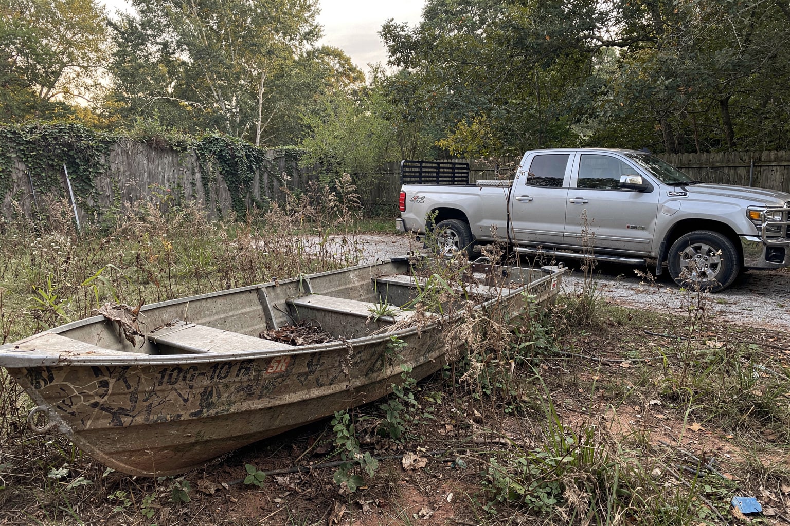 Junk boat removal Raleigh NC deteriorated boat among weeds ready for disposal