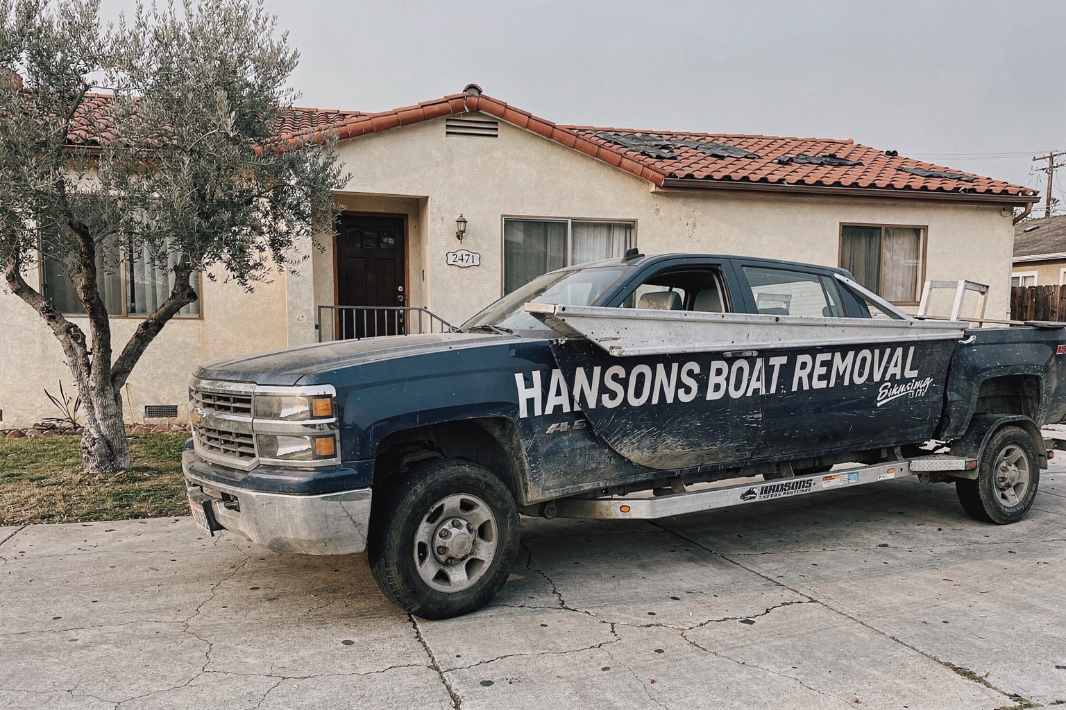 Junk fiberglass boat removal on trailer in San Francisco residential driveway, ready for disposal