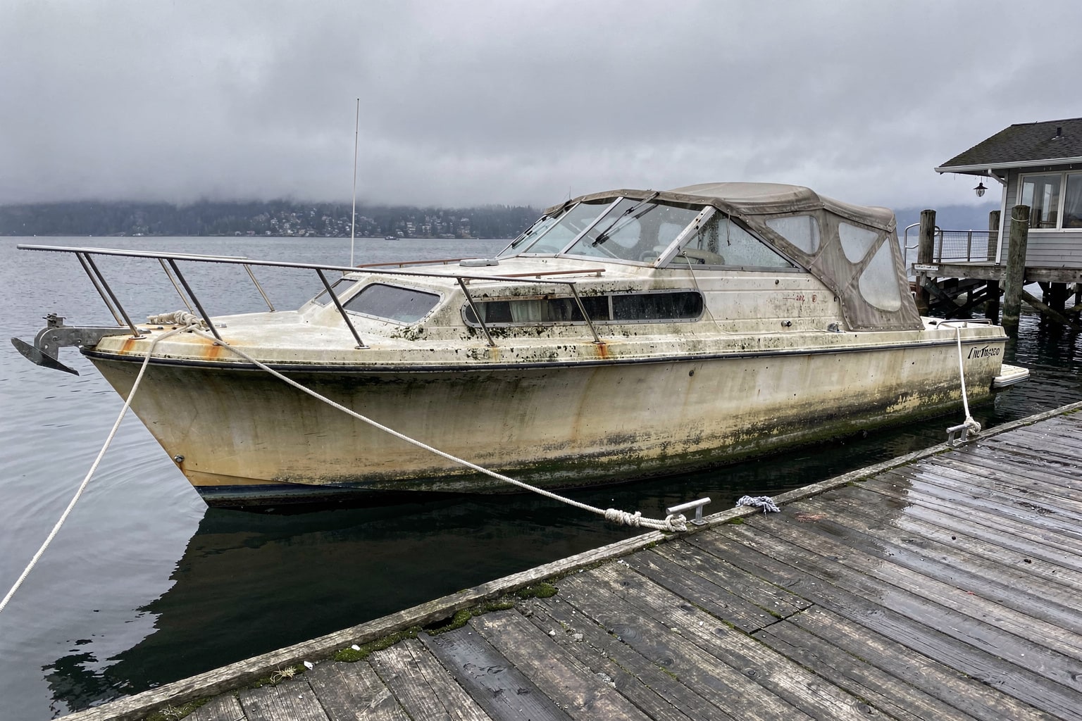 Junk boat removal Seattle: weathered 22-foot cabin cruiser moored at Ballard marina dock ready for disposal