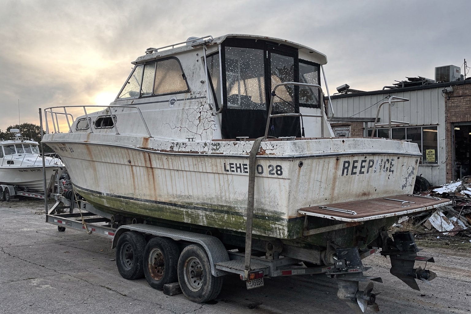 Marine salvage boat disposal at Tennessee salvage yard with 28-foot cabin cruiser on hydraulic lifting equipment