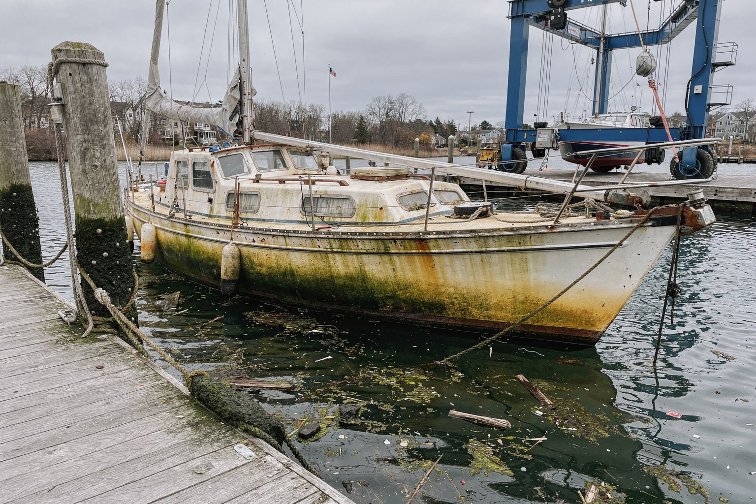 Abandoned 28-foot sailboat moored at weathered Providence Rhode Island marina dock for junk boat salvage removal