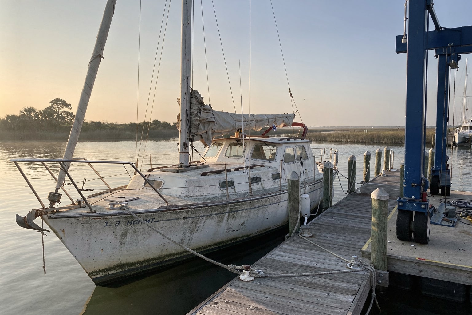 Marine salvage boat removal at South Carolina marina dock, large sailboat prepared for pickup by travel-lift crane